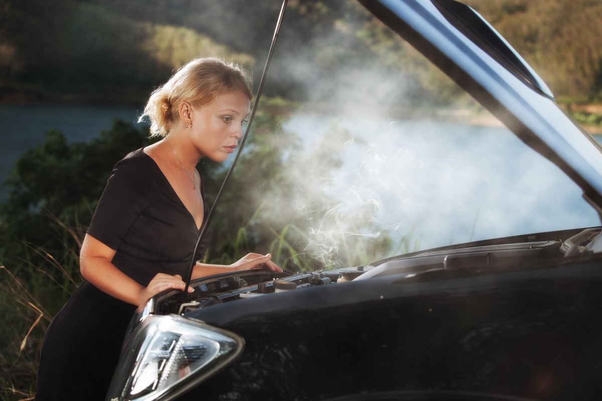 woman looking at engine with steam coming out 