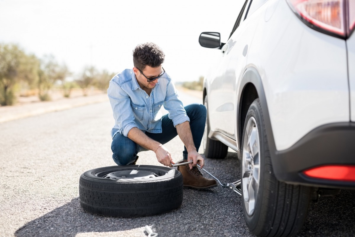 man changing a tire on side of road